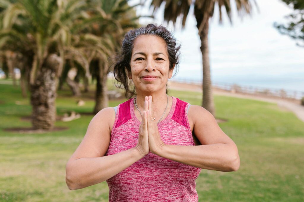 Woman practicing yoga in a sunny outdoor park setting, promoting health and balance.